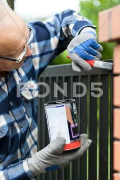 Handyman painting metal fence Stock Photos