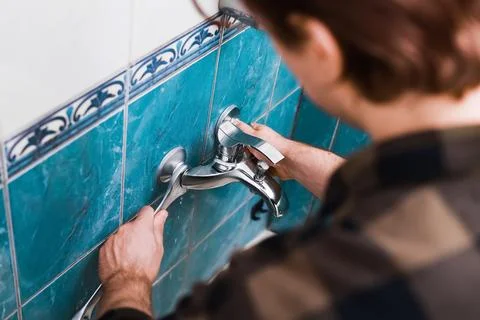 A handyman performs a faucet replacement using a wrench for plumbing DIY re.. Stock Photos