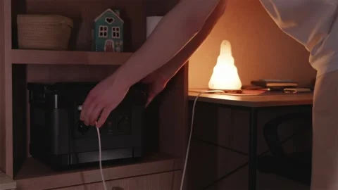 Handyman plugging cable of modern nightlight into portable battery power st.. Stock Footage 336653718