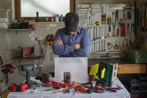 Handyman posing in front of a bench with work tools. Stock Photos