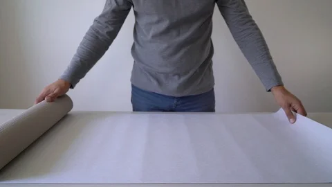 Handyman preparing new wallpaper roll for marking on table indoor Stock Footage 100881813