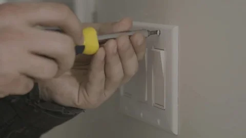 A handyman removes a light switch cover off of the wall. Vídeos de archivo 75889344