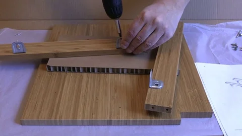 Handyman with screwdriver following instructions to assemble cupboard  Stock Footage 85265309
