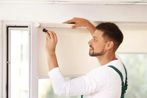 Handyman with screwdriver installing roller window blind indoors Stock Photos