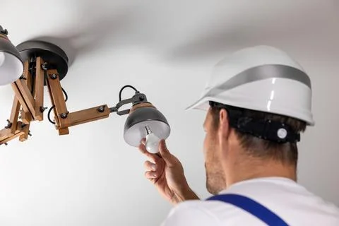 Handyman services. electrician replace led light bulb in ceiling lamp at home Stock Photos