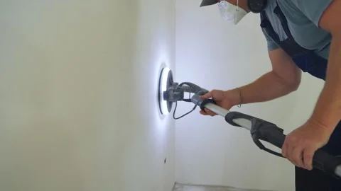 Handyman smooths plastered wall using grinder, sanding tool, construction Stock Footage 319210835