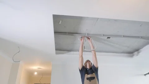 Handyman takes huge wire with bubble from white ceiling Stock Footage 106377080