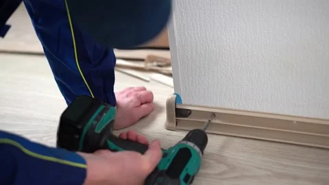 Handyman in uniform doing servise work. Tightening screws, removing the plinth Stock Footage 186934328