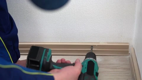 Handyman in uniform doing servise work. Tightening screws, removing the plinth Stock Footage 186934439