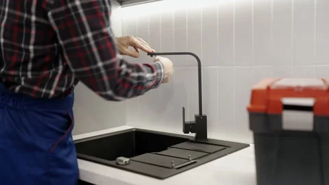 Handyman in uniform finishing kitchen sink installment, plumbing services Vídeo Stock 231574422