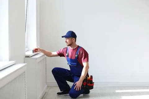 Handyman in uniform working with building level indoors. Professional constru Fotos de archivo