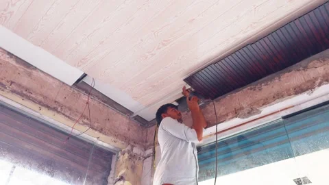 Handyman uses drill tool for sheet attachment above Stock Footage 313277693