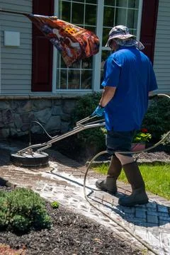 Handyman using a circular power washer to clean a brick walkway in front of.. Stock Photos