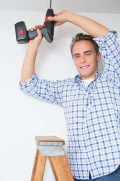 Handyman using cordless drill to the ceiling Stock Photos