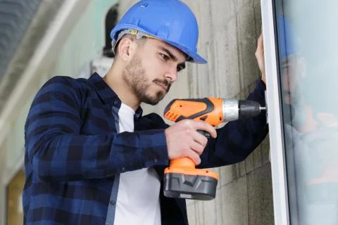 Handyman using a cordless screwdriver to install a window Stock Photos