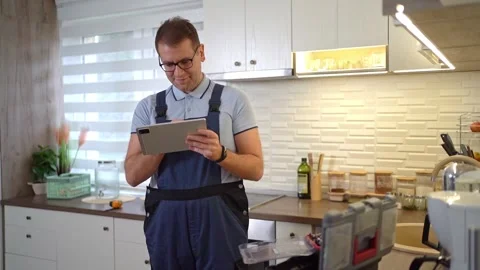 Handyman using a digital tablet in a customers kitchen Stock Footage 321893872
