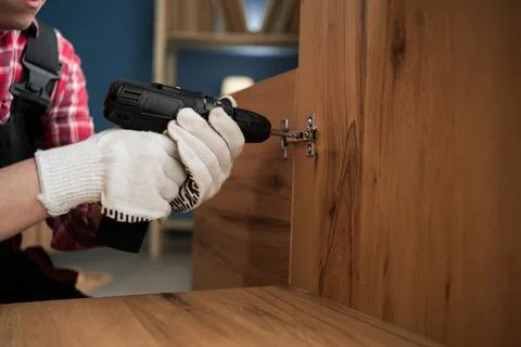 Handyman using electric drill for fixing hinges while doing furniture assem.. Stock Photos