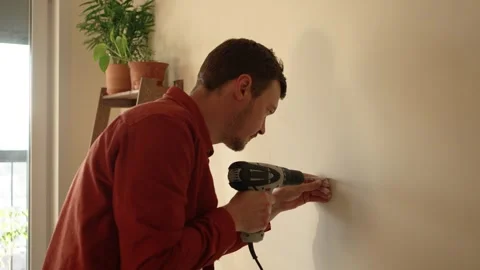 Handyman using a power drill for home improvement project, mounting a Stock Footage 344292909