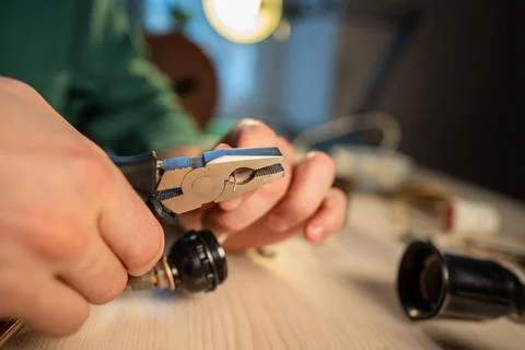 Handyman working at home workshop, using pliers tool to repair old light bulb Stock Photos