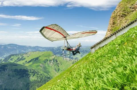 Hang glider pilot jumps from steep slope Stock Photos