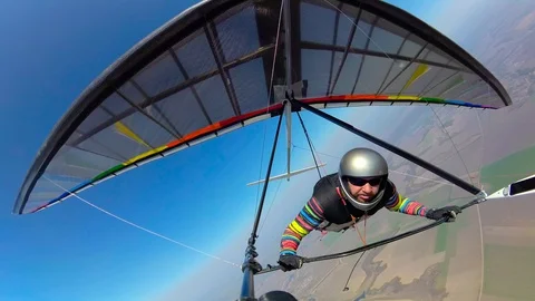 Hang glider pilot shows thumb up while flying high above ground Stock Footage 128079415
