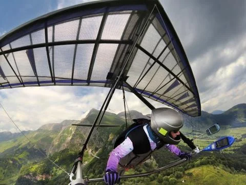 Hang glider pilot soars high above mountain peaks. Photos