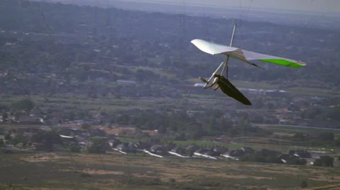 Hang glider soaring through air with valley and mountains seen in distance. Video stock 52224086