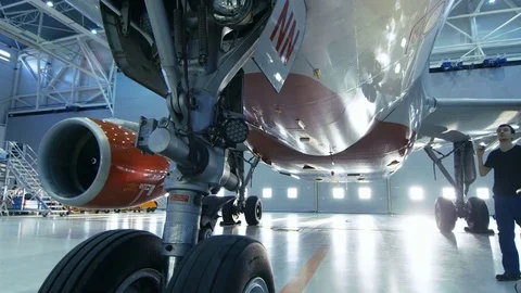 In a Hangar Aircraft Maintenance Engineer/ Technician/ Mechanic Inspects Plane Stock Footage 77260531