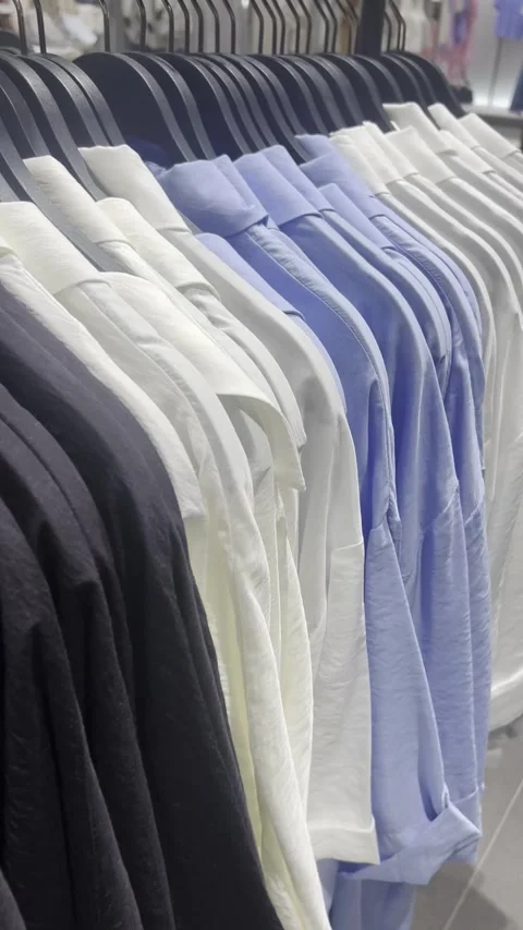 Hangers filled with basic casual shirts, in a modern boutique Video stock 311129739