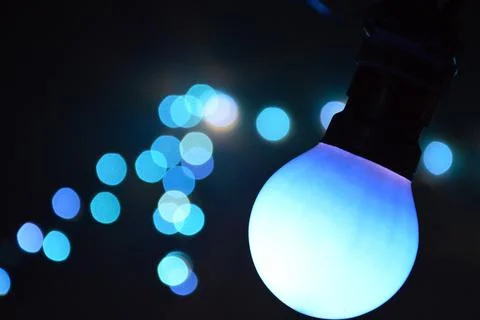 Hanging blue retro light bulb bokeh at night. Stock Photos