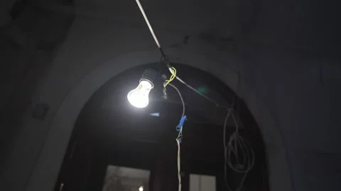 Hanging bulb on wire illuminates room with high ceilings Stock Footage 316087015
