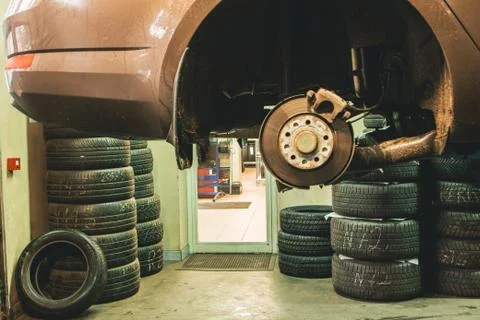 Hanging car in a auto service workshop on the background of used tires Stock Photos