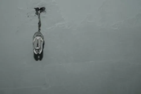 Hanging from the ceiling is an old energy-saving light bulb. Repair in the house Stock Photos