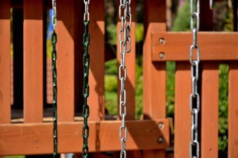 Hanging chains against the backdrop of a hedge in the park.	 Stock Photos