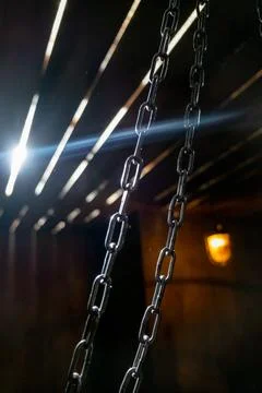 Hanging Chains Cross a Beam of Sunlight Foto stock