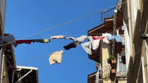 Hanging on clothes drying in the wind between old residential buildings in a Stock Footage 321347779