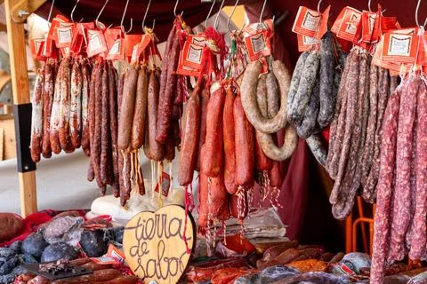 Hanging cured sausages with red tags at market stall Stockfoto's