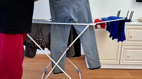 Hanging Freshly Washed Clothes on Indoor Drying Rack at Home Stock Footage 338317560