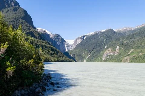 Hanging glacier generating waterfall flowing into grey lake in patagonia chile Stock Photos