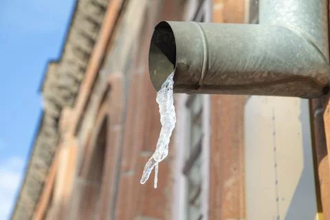 Hanging icicles on the edge of the pipe. Stock Photos