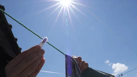 Hanging laundry to dry under the bright sun on a clear day outdoors Stock-Footage 292444134
