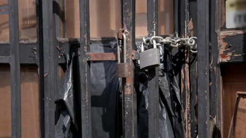 Hanging metal padlock on rusty grate cell with black package and cardboard Stock Footage 236661136