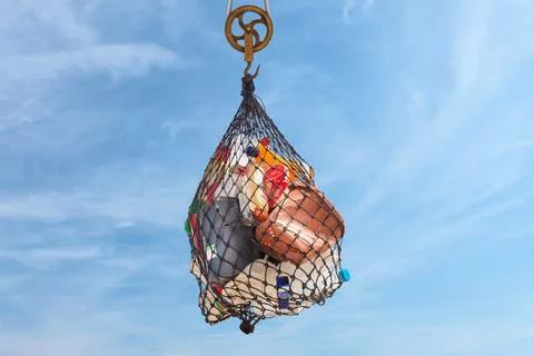 Hanging net with plastic garbage bottles, cans and containers in front of a b Stock Photos