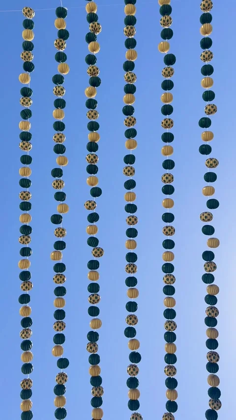 Hanging paper lanterns dancing in the wind against a clear blue sky Stock Footage 346596325