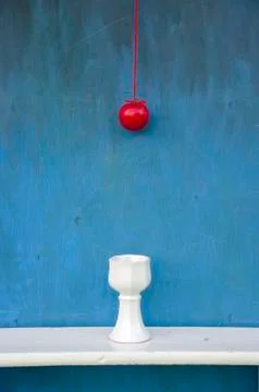 Hanging red apple on string and white vase Stock Photos