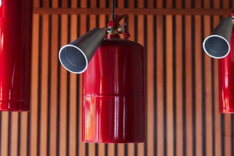 Hanging red fire extinguishers on the ceiling on a wooden wall background Stock Photos
