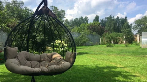 Hanging rocking chair on a plot near the house, on a green lawn Stock Footage 207683304