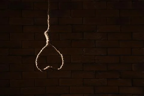 Hanging rope with loop on dark brick background. Suicide concept Stock Photos