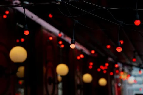 Hanging string lights with glowing red bulbs suspended on dark cables Foto stock