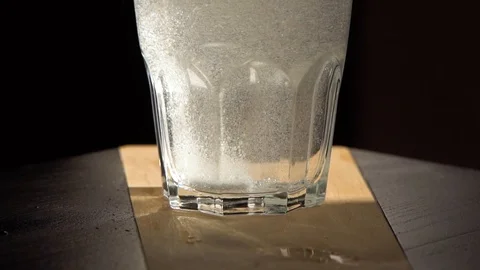 A hangover pill dissolves at the bottom of a glass of water. Many bubbles Stock Footage 119712235